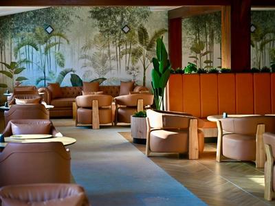 Moderne lounge met comfortabele fauteuils en planten, muur met natuurschildering.