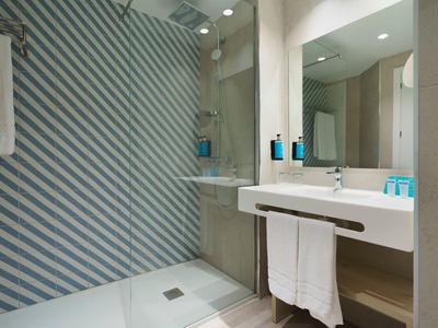 Douche moderne dans une salle de bain avec un mur en carreaux diagonaux bleus et blancs.