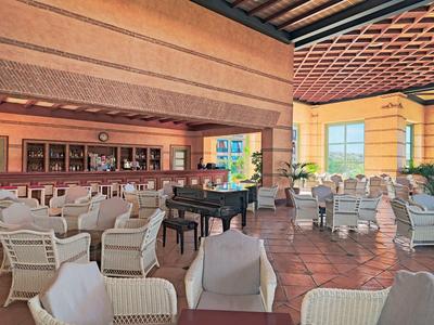 Ampia e luminosa lounge dell'hotel con posti a sedere e pianoforte a coda sotto grandi finestre.