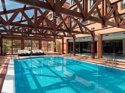 Piscina coperta con acqua blu, travi di legno e lettini sullo sfondo