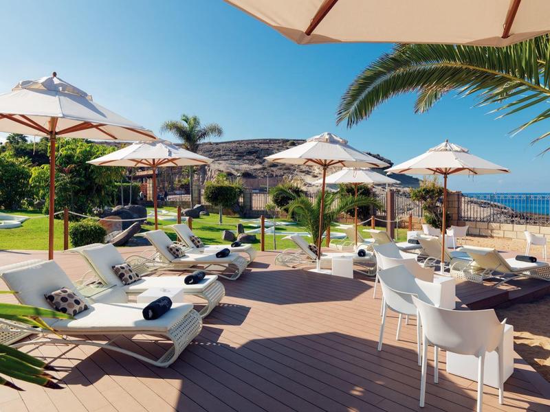 Terrazza dell'hotel con lettini, ombrelloni e vista sul mare in una giornata di sole.