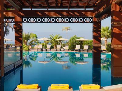 A covered pool with lounge chairs and tropical plants in the background.