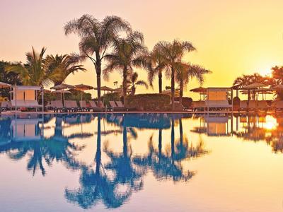 Calm pool at sunset with palm trees and sun loungers
