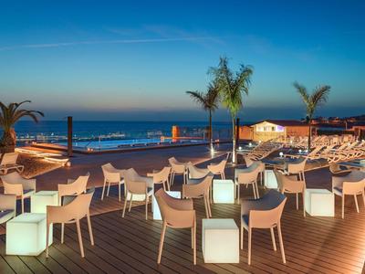 Evening hotel terrace with modern seating and a view of the sea.