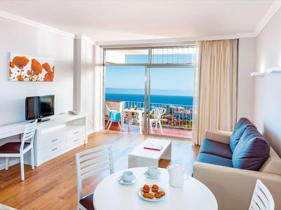 Bright living room with sea view, dining table, sofa, and balcony with chairs