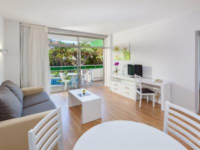 Bright living room with gray-blue sofa, white table, and access to a terrace overlooking the pool.