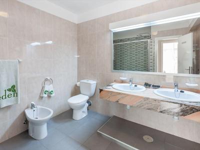 Modern bathroom area with double sinks, toilet, bidet, and large mirrors.