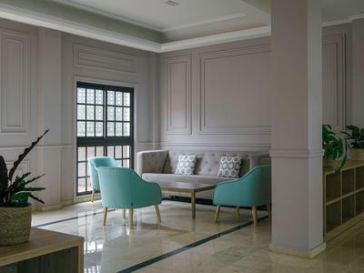 Modern corner with two turquoise armchairs, sofa, and large window in a hotel room.