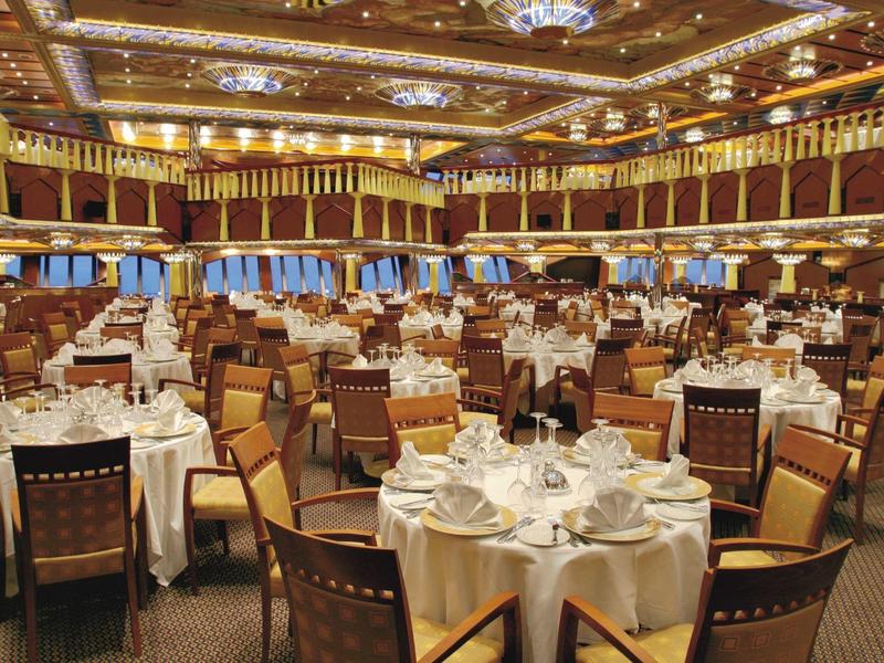 Großer, eleganter Bankettsaal mit runden, weiß gedeckten Tischen und Holzmöbeln unter Golddecke.