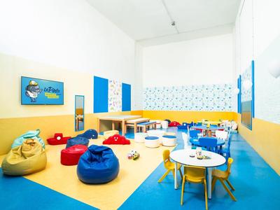 Sala de juegos para niños colorida con pufs, mesas, sillas y juguetes en colores vivos.