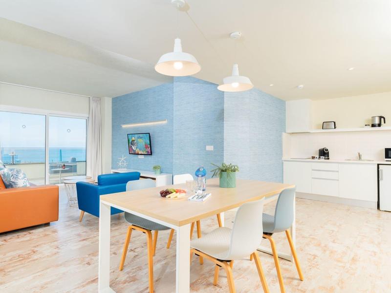 Luminoso apartamento moderno con comedor, cocina abierta y vistas al mar desde la ventana.
