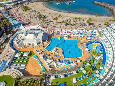 Vista aerea della piscina del resort con lettini e spiaggia sullo sfondo.