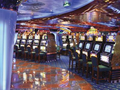 Interior view of a casino with slot machines and chairs on a shiny floor.