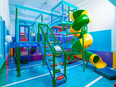 Indoor kids play area with colorful slides and climbing structures in a bright room.
