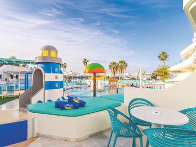 Parasols colorés et piscine avec chaises longues sous un ciel bleu.