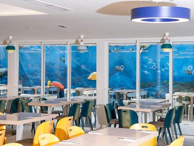 Salle à manger moderne avec fenêtres sur thème sous-marin et chaises colorées.