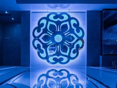 Modern blue-lit hotel interior with large artistic wall decoration and reflection on shiny floor