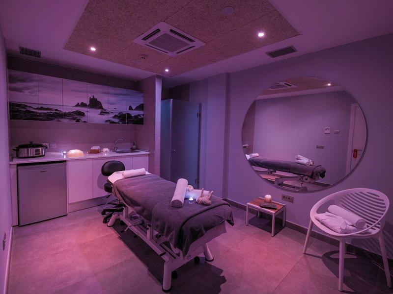 A stylishly furnished massage and wellness room with dim lighting and a massage table.