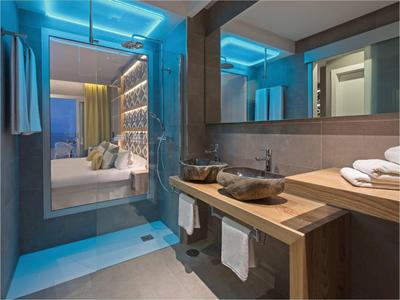Bagno moderno con mobili in legno e specchio illuminato di blu nella camera d'hotel.