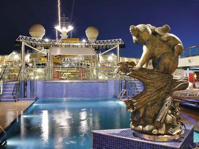 Verlichte zwembad op een cruiseschip met een glanzend dolfijnbeeld bij nacht