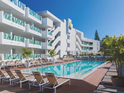 Moderner Hotelpool mit Liegestühlen bei sonnigem Himmel und weißem Gebäude im Hintergrund