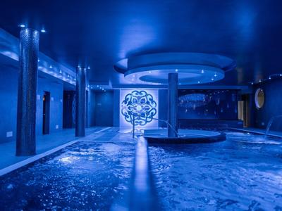 Vnitřní bazén s modrým osvětlením a kulatým sloupem v luxusním hotelu