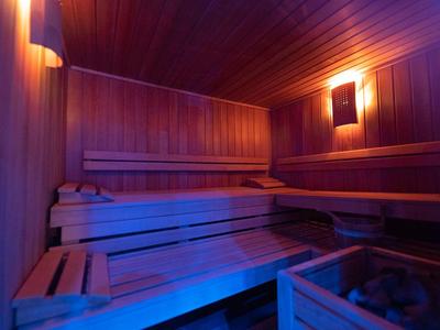 Interior de una sauna con bancos de madera y luz suave para relajación en el hotel.