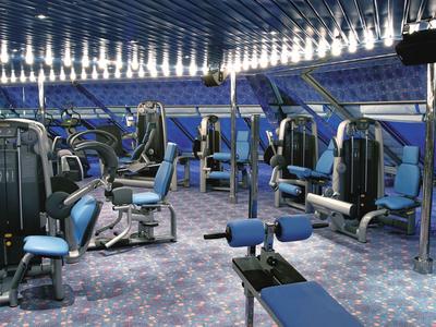 Palestra moderna con varie attrezzature e sedili imbottiti blu.