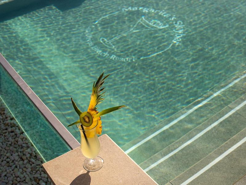 Bevanda rinfrescante con ananas decorato vicino a una piscina con logo nell'acqua.