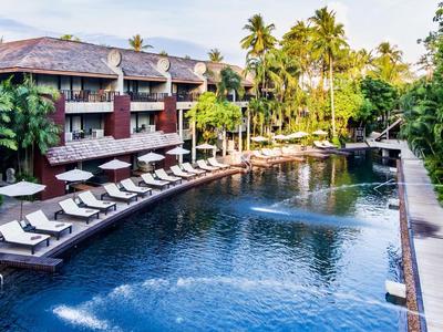 Großer Außenpool mit Liegestühlen und tropischer Vegetation an einem Hotel.