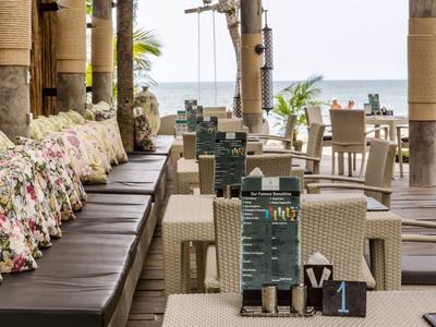 Gemütlicher Außenbereich eines Restaurants mit Blick aufs Meer und Sitzgelegenheiten mit Kissen.