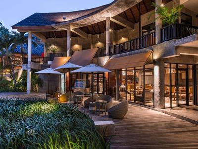 Abendlicher Blick auf ein modernes Hotel mit beleuchtetem Außenbereich und Garten.