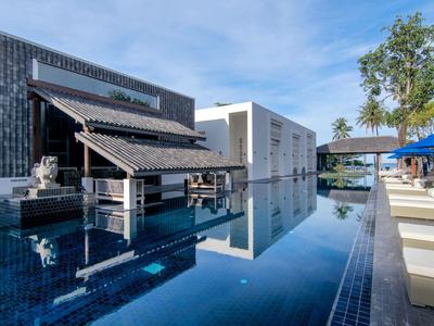 Moderner Poolbereich mit stilvollen Gebäuden und Liegestühlen bei klarem Himmel.