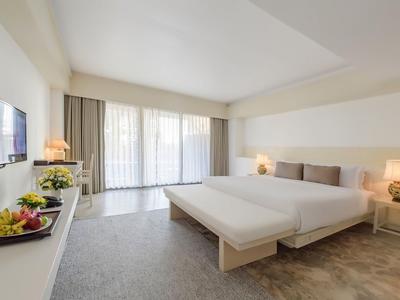 Helles, minimalistisches Hotelzimmer mit zwei Betten und Balkon mit Vorhängen.