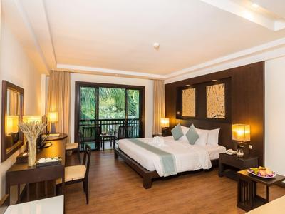 Ein modernes Hotelzimmer mit großem Bett, Schreibtisch und Balkon mit Blick ins Grüne.