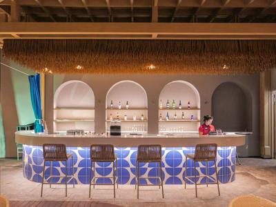 Moderner Hotelbarbereich mit beleuchtetem Tresen, sechs Hockern und architektonischen Rundbögen.