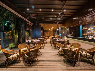 Gemütliche Hotelbar mit Holzboden, Rattanmöbeln und stimmungsvoller Beleuchtung am Abend.