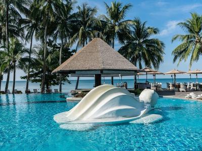 Pool mit einer Muschel-Figur im Wasser und Palmen im Hintergrund bei klarem Himmel