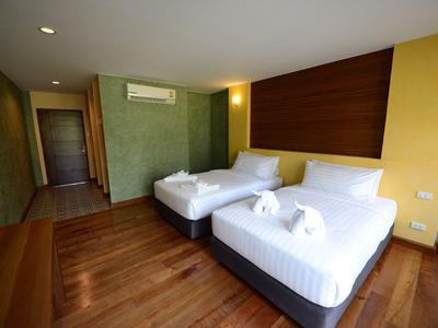 Modernes Hotelzimmer mit zwei Einzelbetten, Holzboden und grün-gelben Wänden.