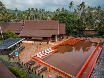 Hotelanlage mit großem rechteckigem Pool, Liegestühlen und tropischer Vegetation im Hintergrund
