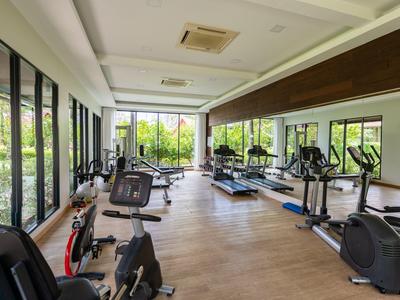 Heller Fitnessraum mit modernen Geräten und großen Fenstern mit Blick ins Grüne.