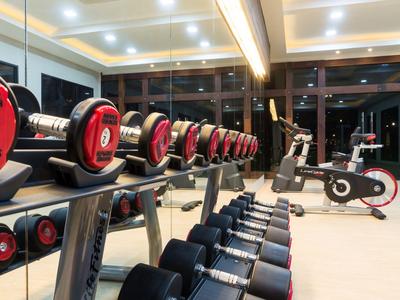 Moderne Fitnessräume mit Hanteln und Trainingsgeräten vor großen Fenstern.