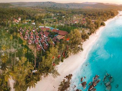 Luftaufnahme eines Resorts am Strand mit türkisfarbenem Wasser und üppiger Vegetation