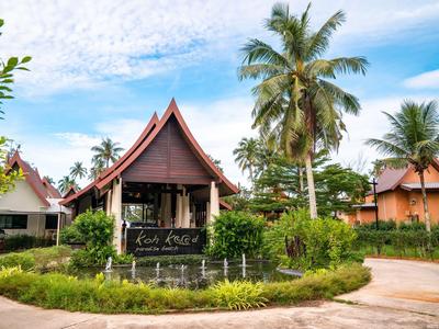 Traditionelles Gebäude mit spitzem Dach in tropischer Gartenanlage mit Palmen.