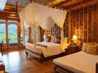 Cozy hotel room with wooden walls and two beds, view of green landscape.