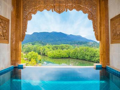 View from a pool with ornate carved frame overlooking green hills and blue sky.