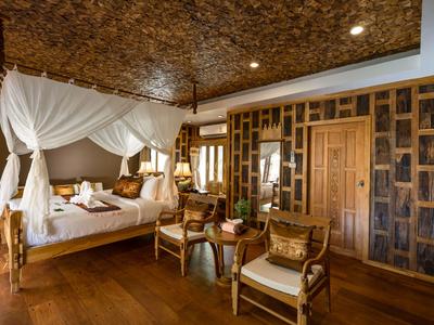 Elegant hotel room with canopy bed, wood paneling, and cozy seating.