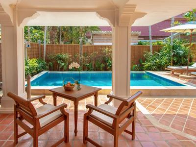 Terrace with wooden table and chairs overlooking a pool and garden area with loungers.