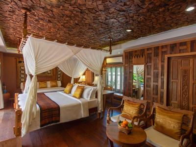 Luxurious hotel room with canopy bed, wooden panels, and cozy seating area.