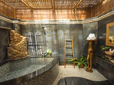 Luxurious bathroom with stone bathtub, wooden accents, and natural lighting.